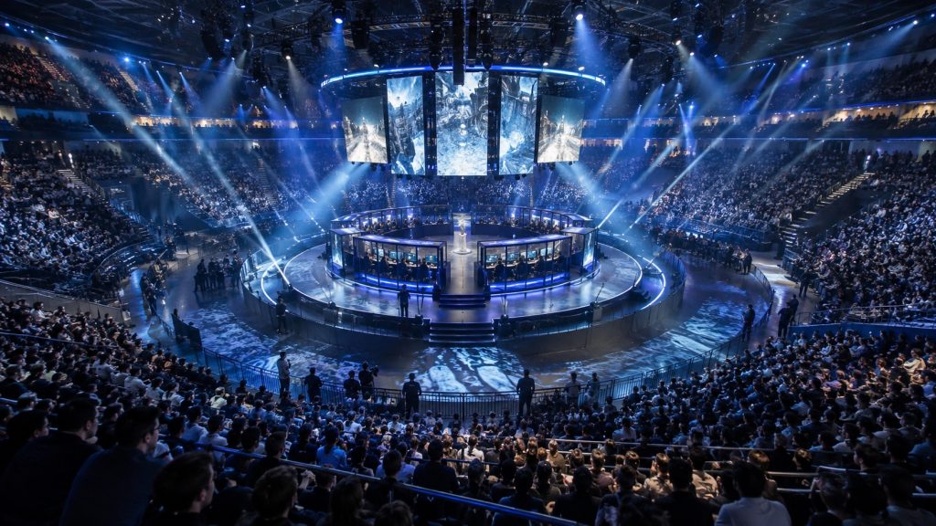 A central esports stage is surrounded by arena seating on every side